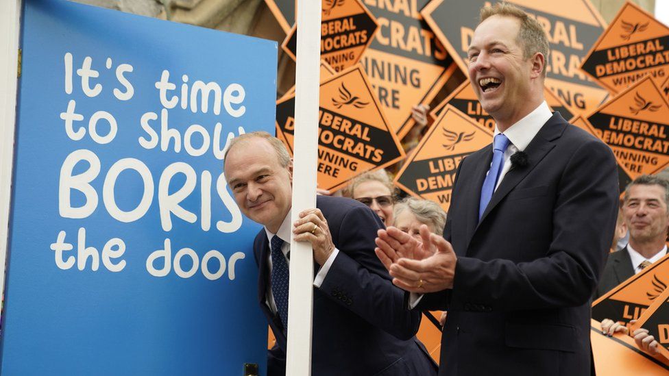 Liberal Democrat's Ed Davey and Richard Foord infront of a door that says 'It's time to show Boris the door'